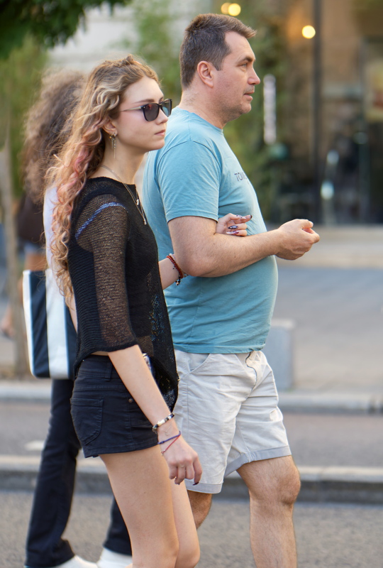 3 - Two individuals walking together on a city street - side view